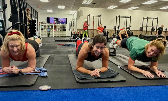 Women holding plank positions during a group fitness class workout at Freedom Fitness O’Fallon.
