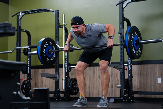 Man performing a bent-over barbell row exercise during a strength and conditioning workout at Freedom Fitness O’Fallon.